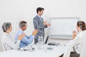 Business team applauding and looking at white screen