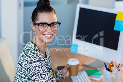 Beautiful brunette smiling at camera and holding coffee