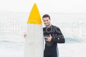 Man in wetsuit with a surfboard on a sunny day