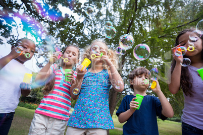 Little friends blowing bubbles in park