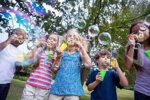 Little friends blowing bubbles in park