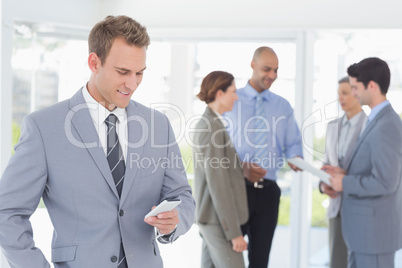 Businessman texting while his colleagues discussing