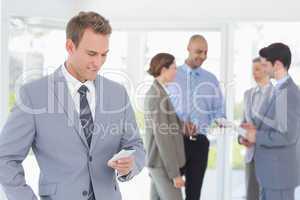 Businessman texting while his colleagues discussing