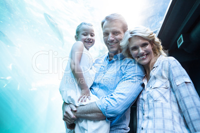 Happy family looking at camera behind a fish tank