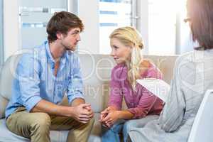 Unsmiling couple talking with their therapist