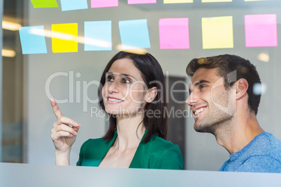 Smiling partners looking at sticky notes