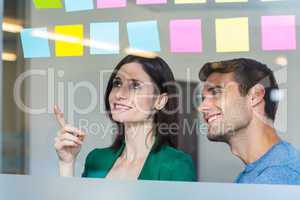 Smiling partners looking at sticky notes