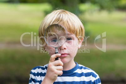 Curious little boy looking through magnifying glass