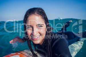 woman in wetsuit with a surfboard on a sunny day