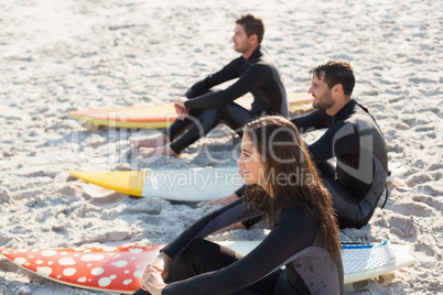 Group of friends on wetsuits with a surfboard on a sunny day