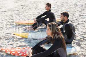 Group of friends on wetsuits with a surfboard on a sunny day