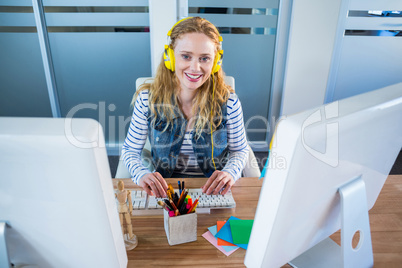 Smiling designer typing on keyboard and listening music