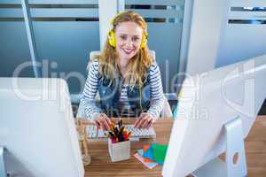 Smiling designer typing on keyboard and listening music