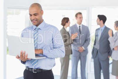 Businessman with his laptop and his colleagues behind