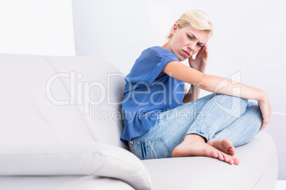 Thoughtful blonde woman sitting on the couch
