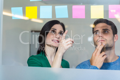 Smiling partners looking at sticky notes