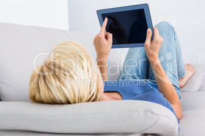 Blonde woman using her tablet on the couch