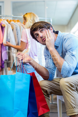 Happy blonde woman doing shopping with her exhausted boyfriend