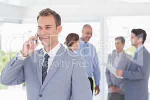 Businessman having phone call while his colleagues discussing