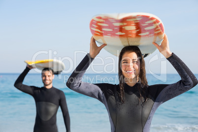 happy couple in wetsuits with surfboard on a sunny day