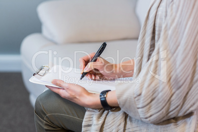 Psychologist sitting on the couch and taking notes