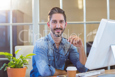 Casual businessman holding glasses and smiling at camera