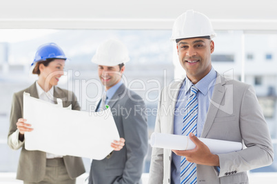 Businessmen and a woman with hard hats and holding blueprint