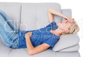 Attractive blonde woman having headache on the couch
