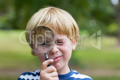 Curious little boy looking through magnifying glass