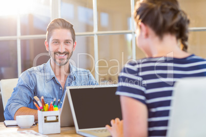 Smiling colleagues working together on laptop