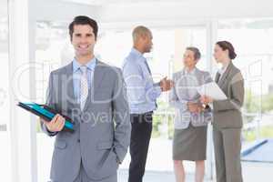 Smiling businessman holding files and looking at camera