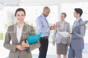 Smiling businesswoman holding files and looking at camera