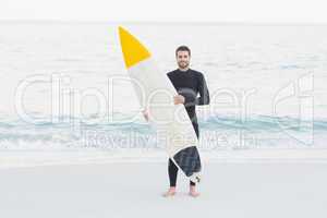 Man in wetsuit with a surfboard on a sunny day