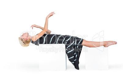 Attractive blonde woman lying on white block
