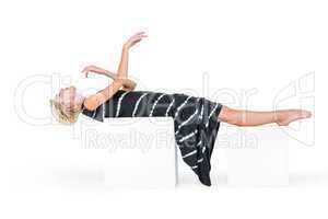 Attractive blonde woman lying on white block