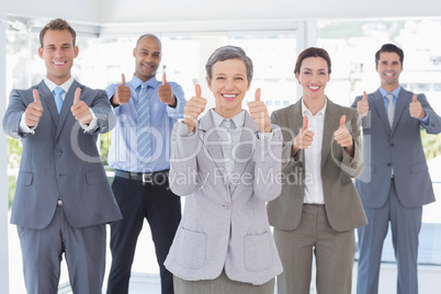 Business team smiling at camera showing thumbs up Business team smiling at camera showing thumbs up