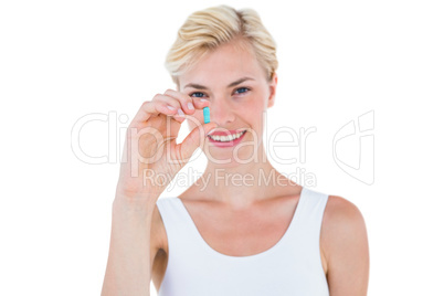 Smiling blonde woman holding blue pill