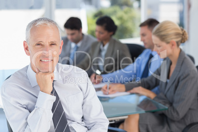 Businessman smiling at camera with colleagues behind