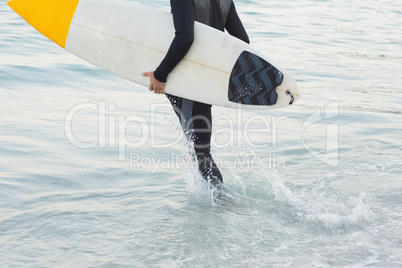 Man in wetsuit with a surfboard on a sunny day