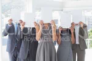 Business colleagues hiding their face with paper