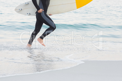 Man in wetsuit with a surfboard on a sunny day