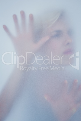 Blonde woman touching frosted glass