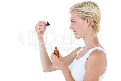 Smiling blonde woman holding bottle of medicine