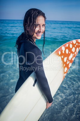 woman in wetsuit with a surfboard on a sunny day