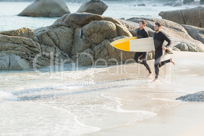 Two men in wetsuits with a surfboard on a sunny day