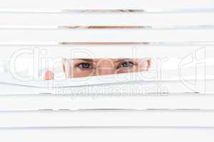 Curious blonde woman looking through venetian blind