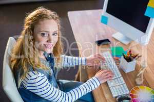 Smiling designer typing on keyboard