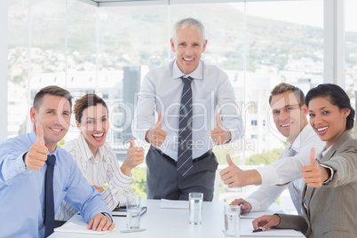 Business team smiling at camera showing thumbs up