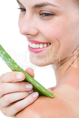 Attractive woman moisturizing her skin with aloe vera leaf