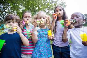 Little friends blowing bubbles in park